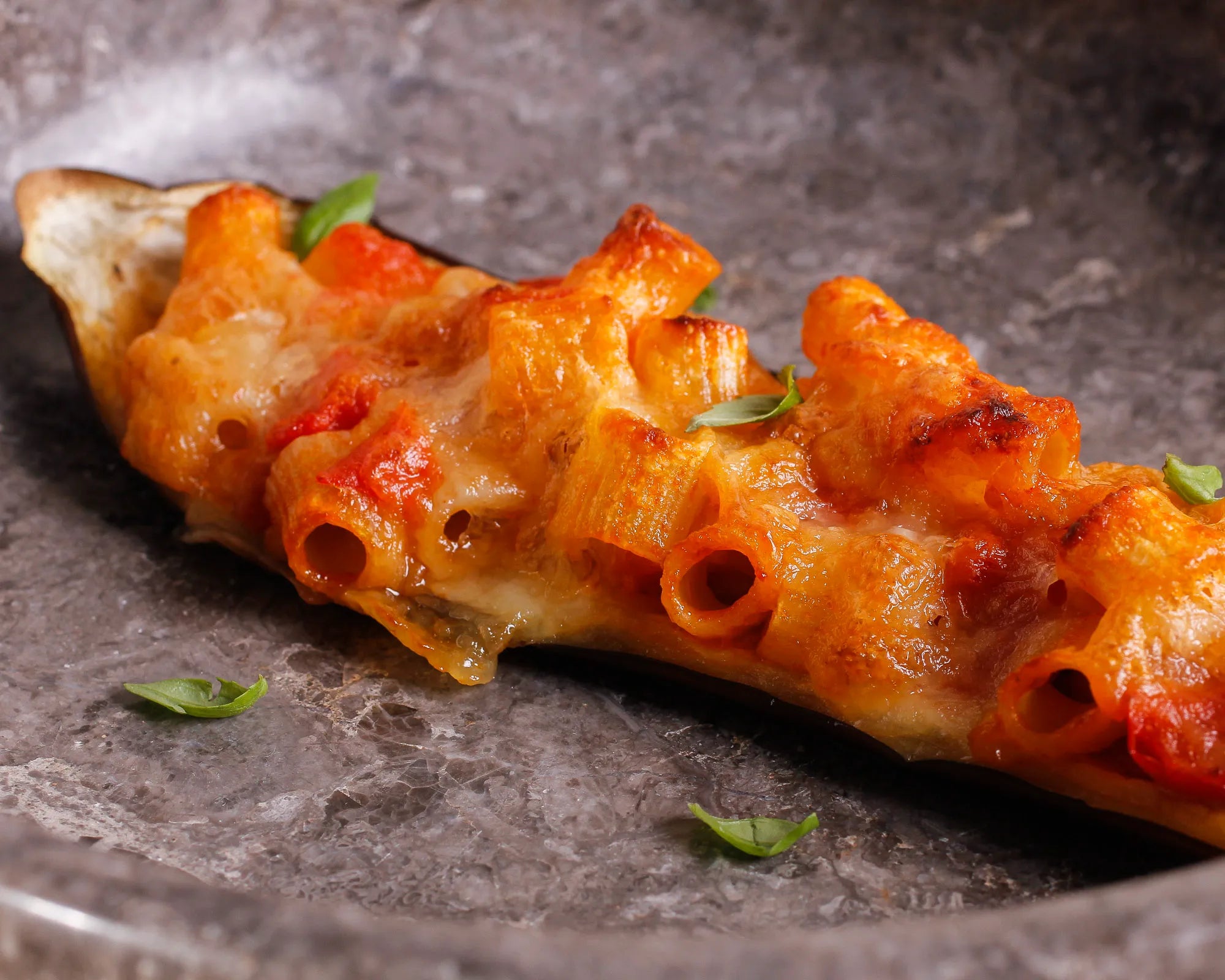 Eggplant stuffed with pasta, cherry tomatoes, eggplant pulp, mozzarella, and parmesan shavings 