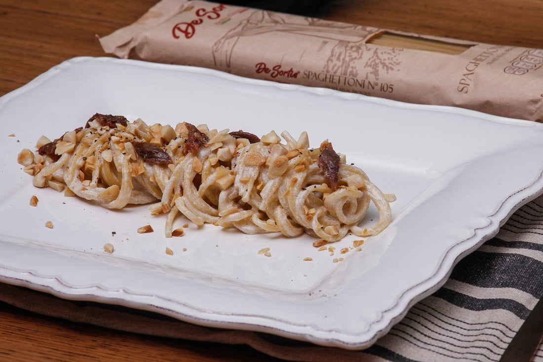 Spaghettoni aglio, olio e acciughe, mantecati in crema di ricotta con mandorle tostate e acciughe sott’olio