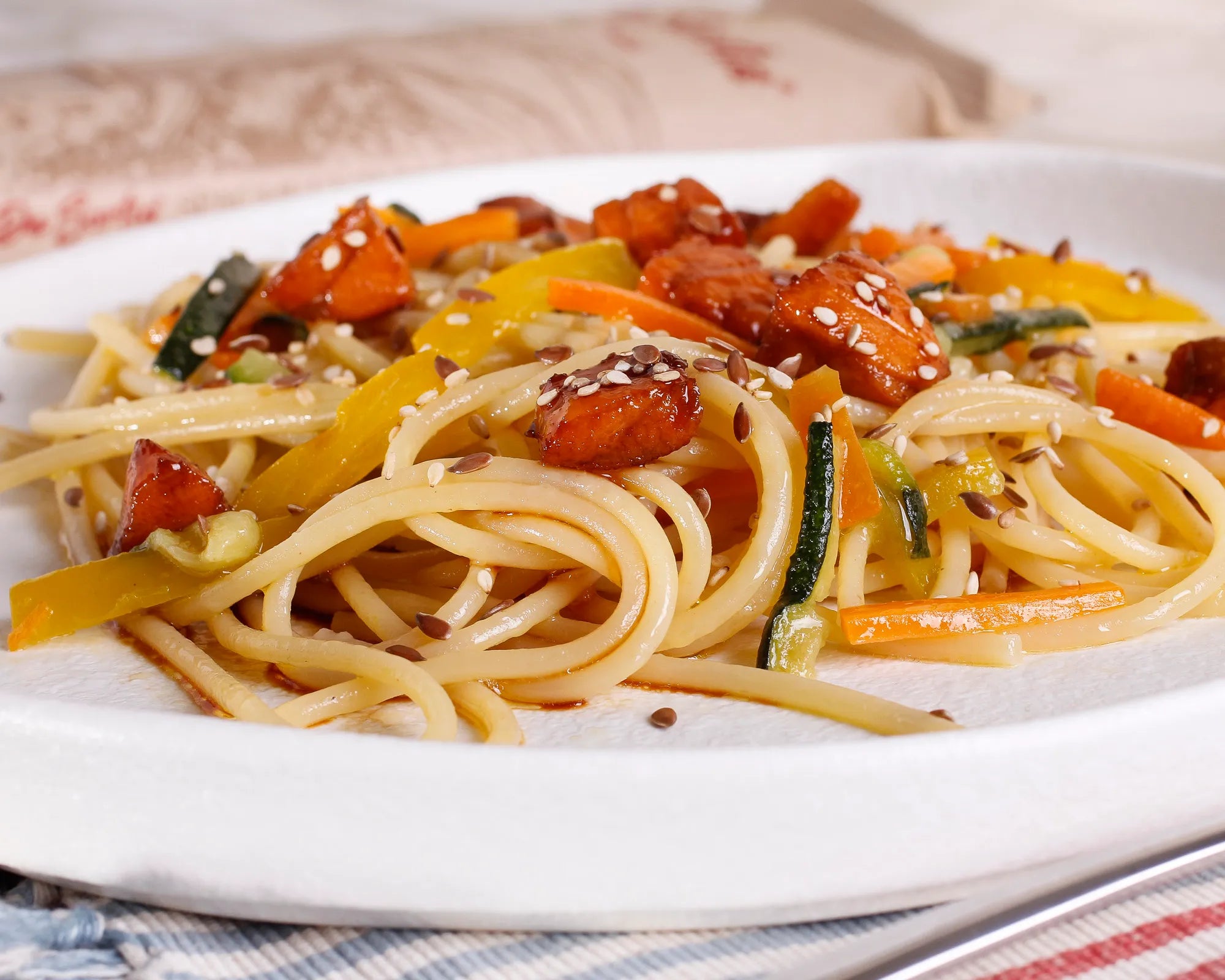 Spaghetti with julienned vegetables (zucchini, peppers, carrots), cubes of salmon glazed with soy and honey and sesame seeds 